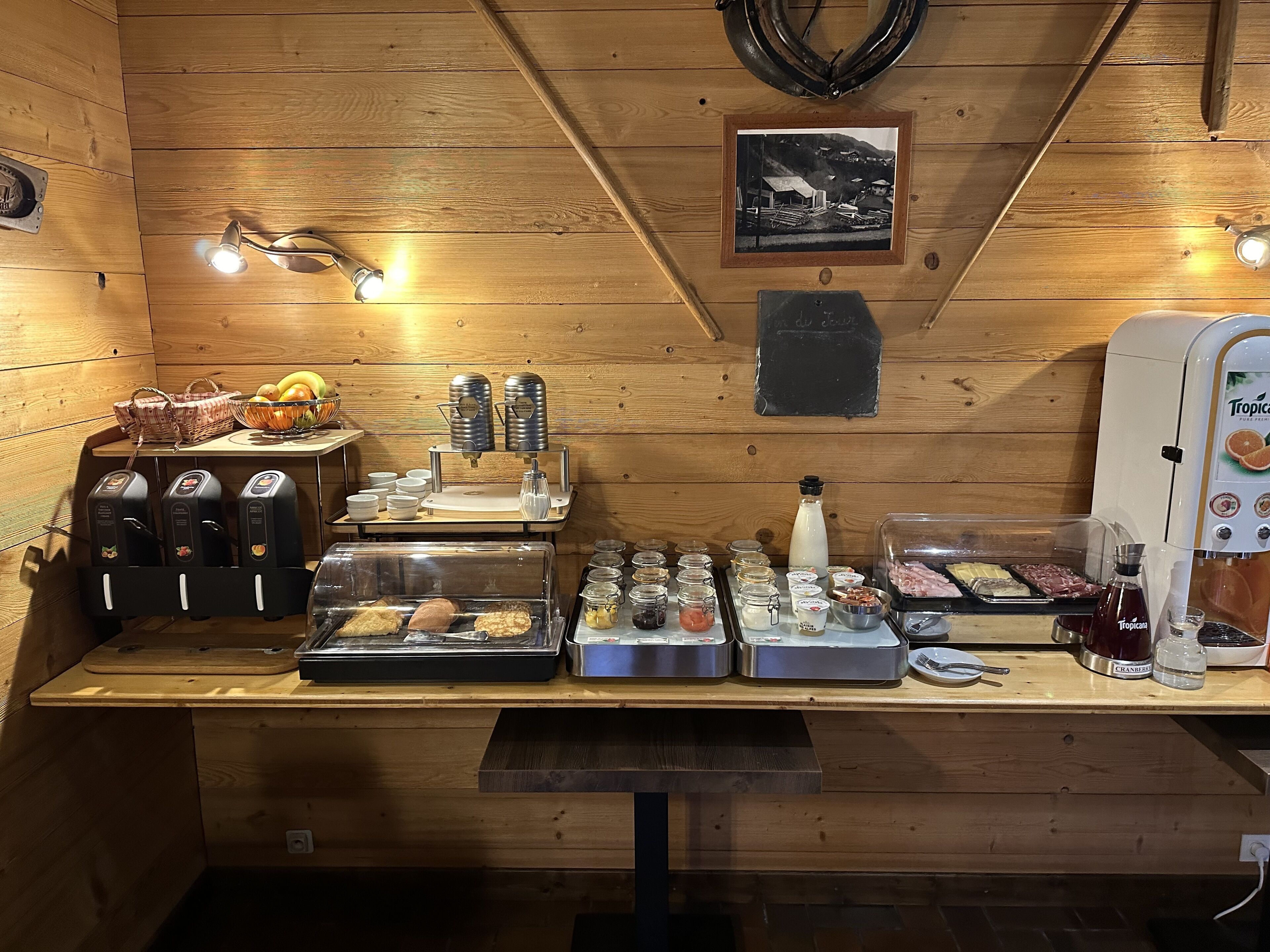 A breakfast bar with coffee machines, a fruit basket, and various food items.