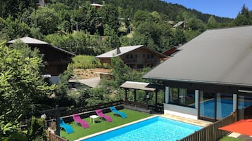 Una piscina al aire libre de temporada, sillones reclinables de piscina