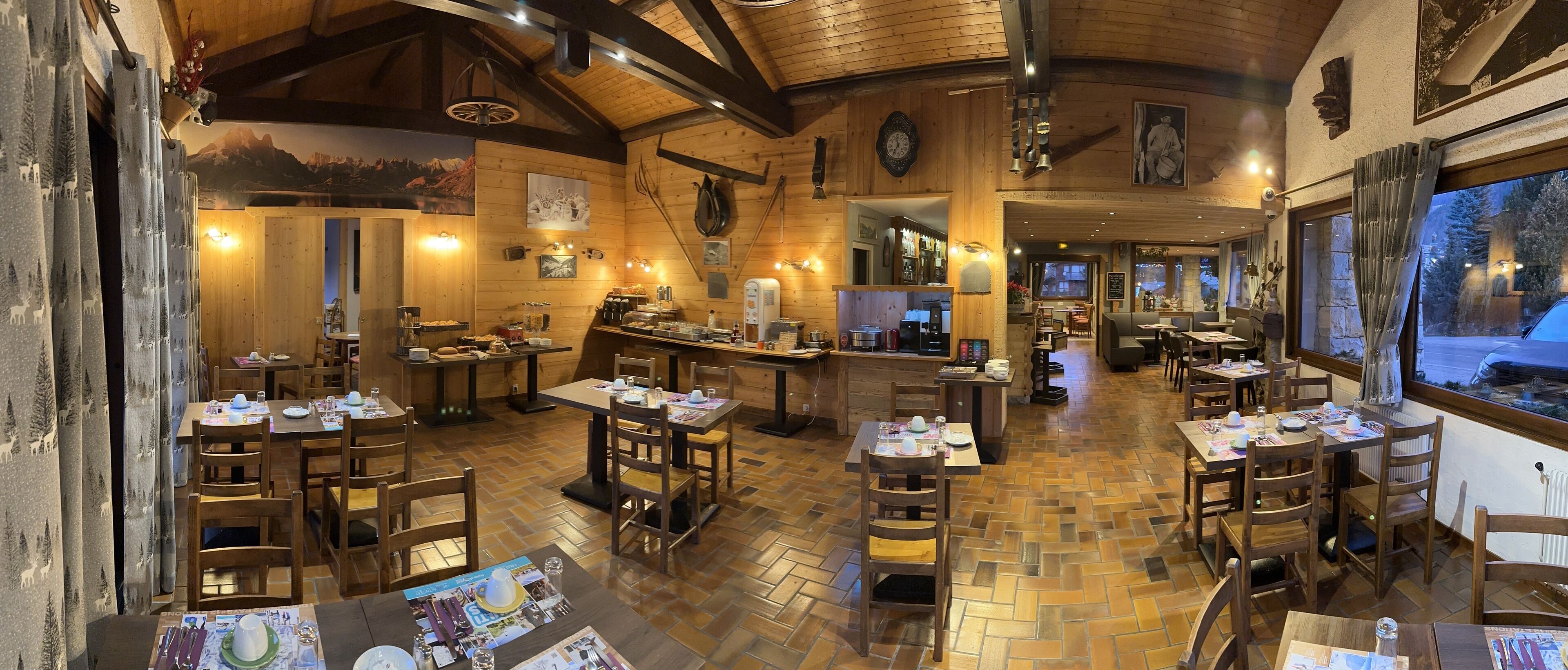 A cozy restaurant with wooden interiors, multiple dining tables, and a bar area.