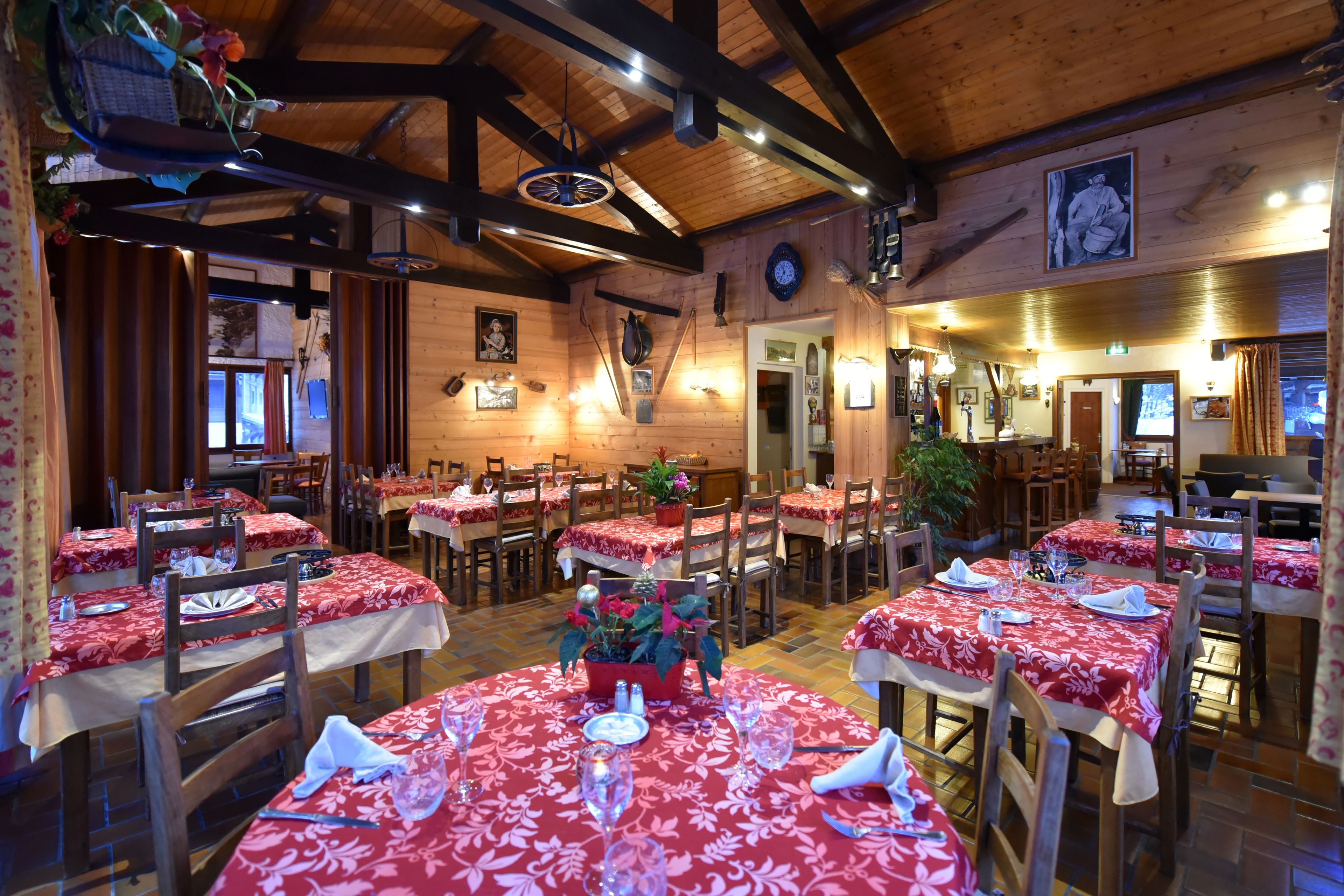 Un restaurante con interiores de madera, manteles rojos y varias mesas y sillas.