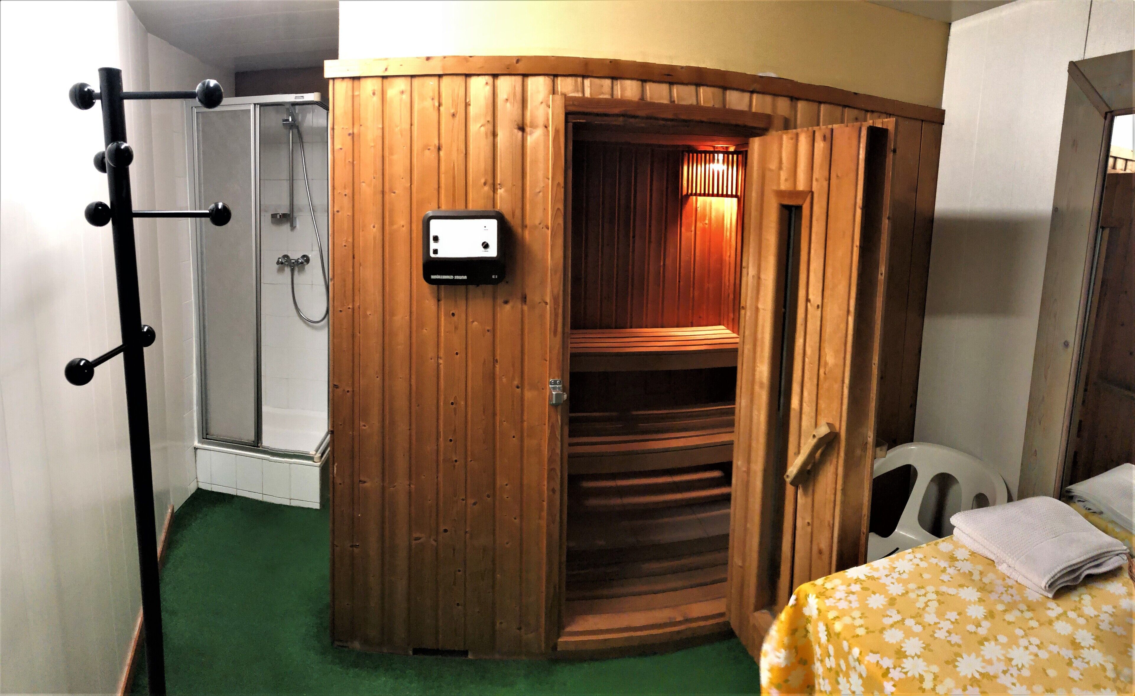 Eine Sauna mit Holzfassade, Glastür und Bedienfeld.