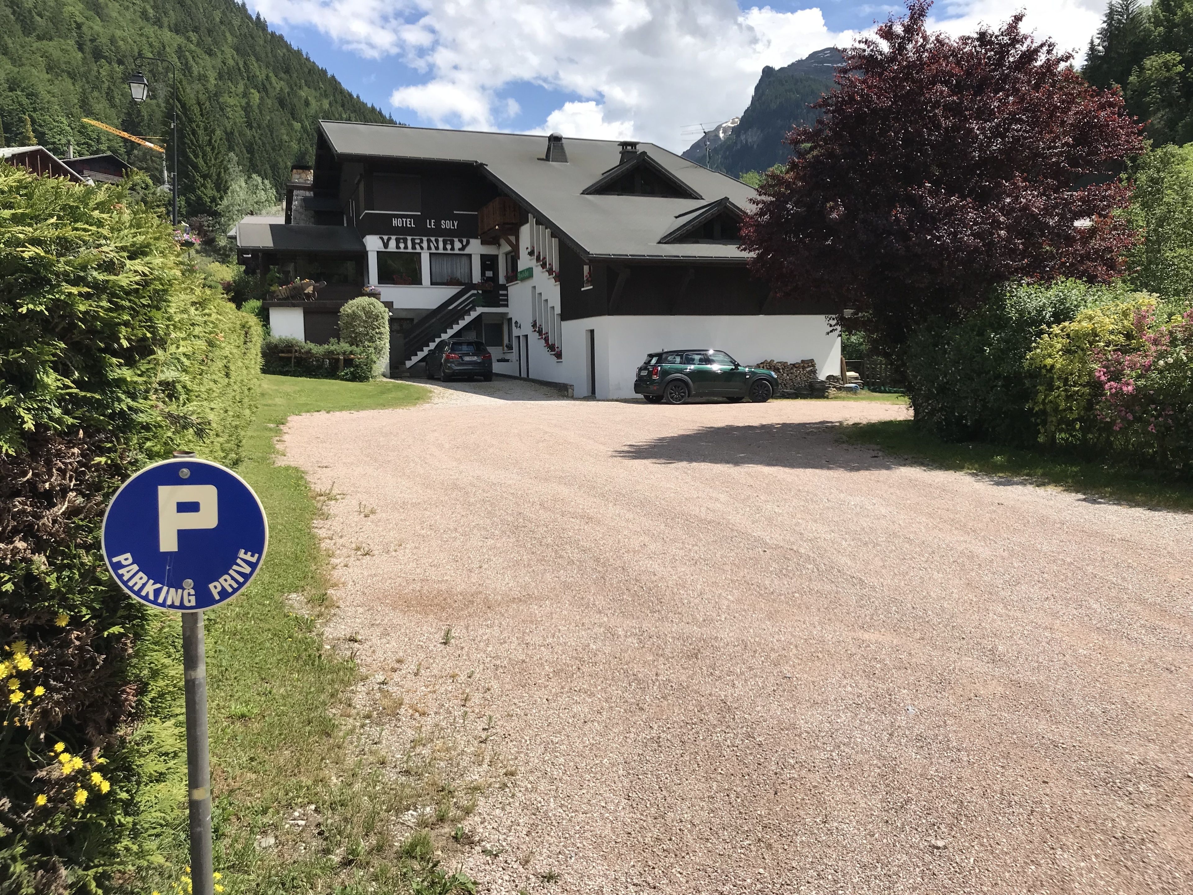 A hotel named 'Varnay' with a gravel driveway leading to a parking area marked by a blue 'PARKING PRIVATE' sign.