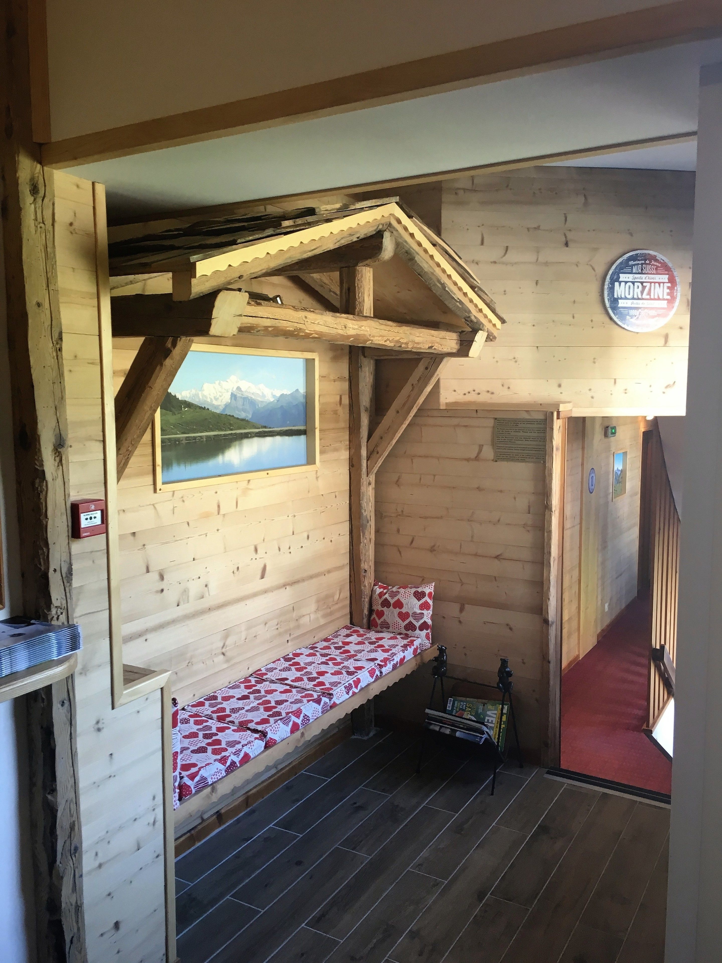 A wooden cabin with a built-in bench, a view of a lake, and a Morzine sign.
