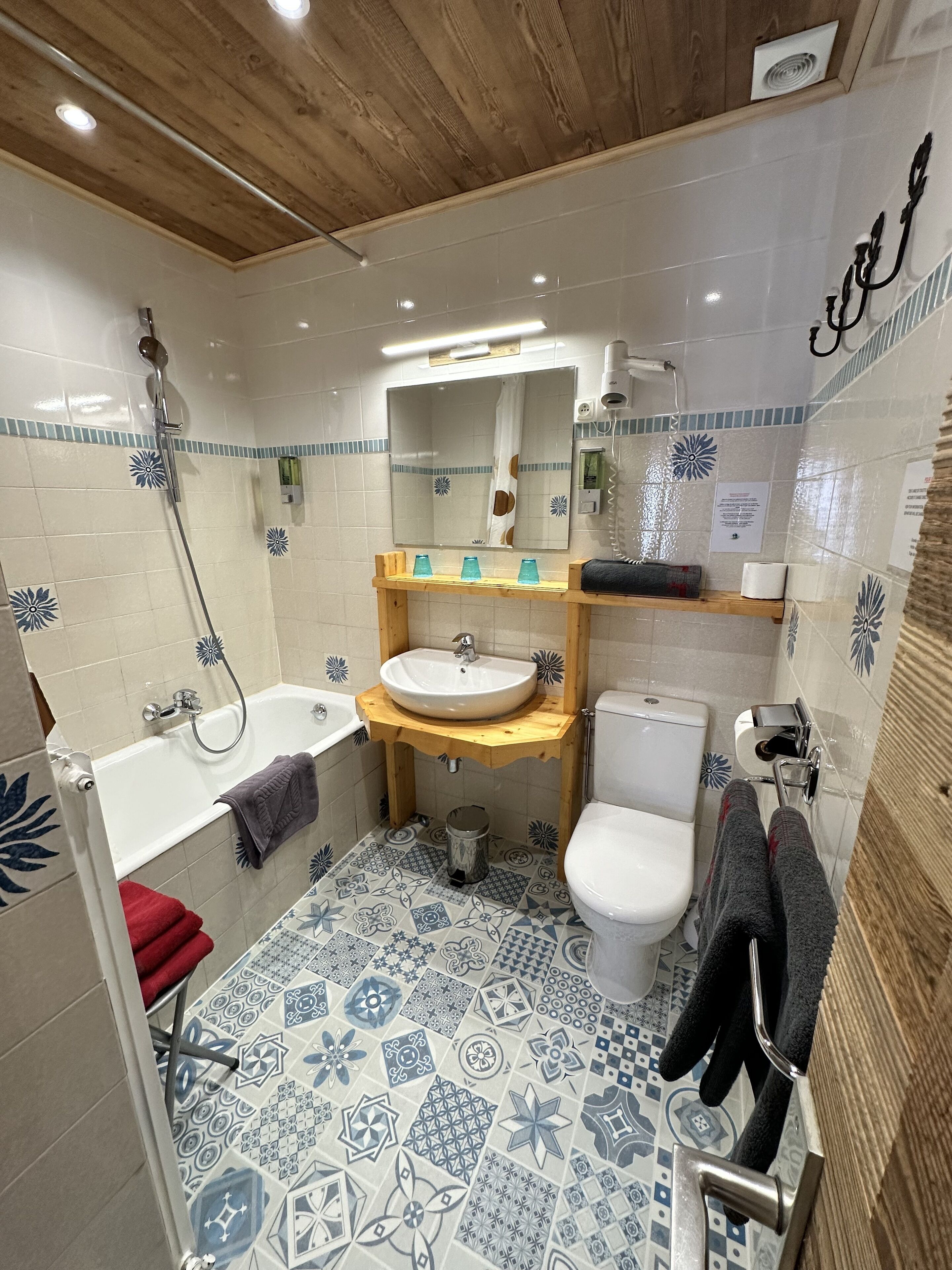 A bathroom with a wooden ceiling, a bathtub, a sink, a toilet, and a shower.