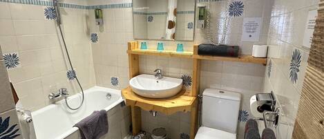 A bathroom with a wooden ceiling, a bathtub, a sink, a toilet, and a shower.
