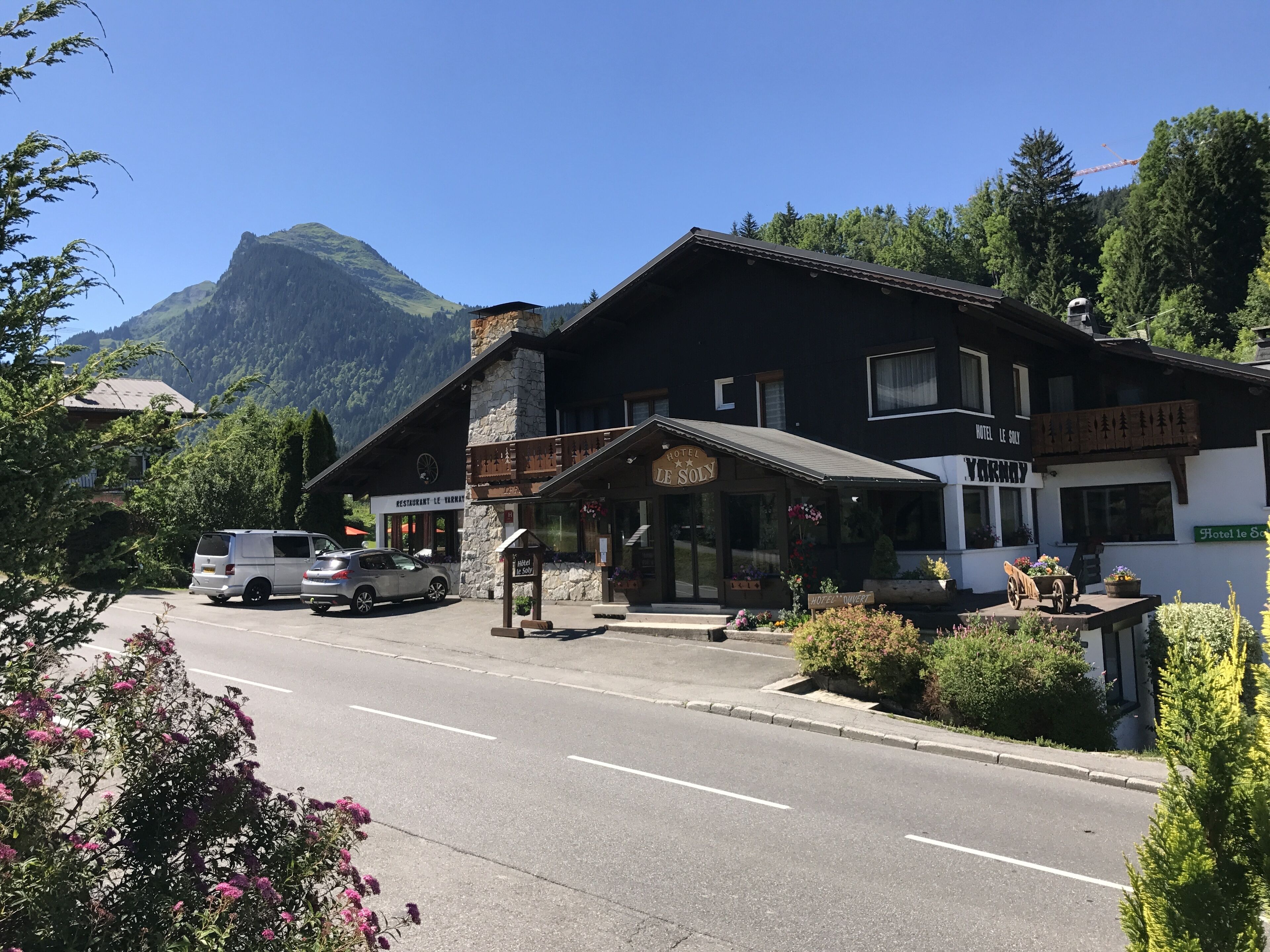 A hotel with a stone facade, a wooden porch, and a mountain backdrop.