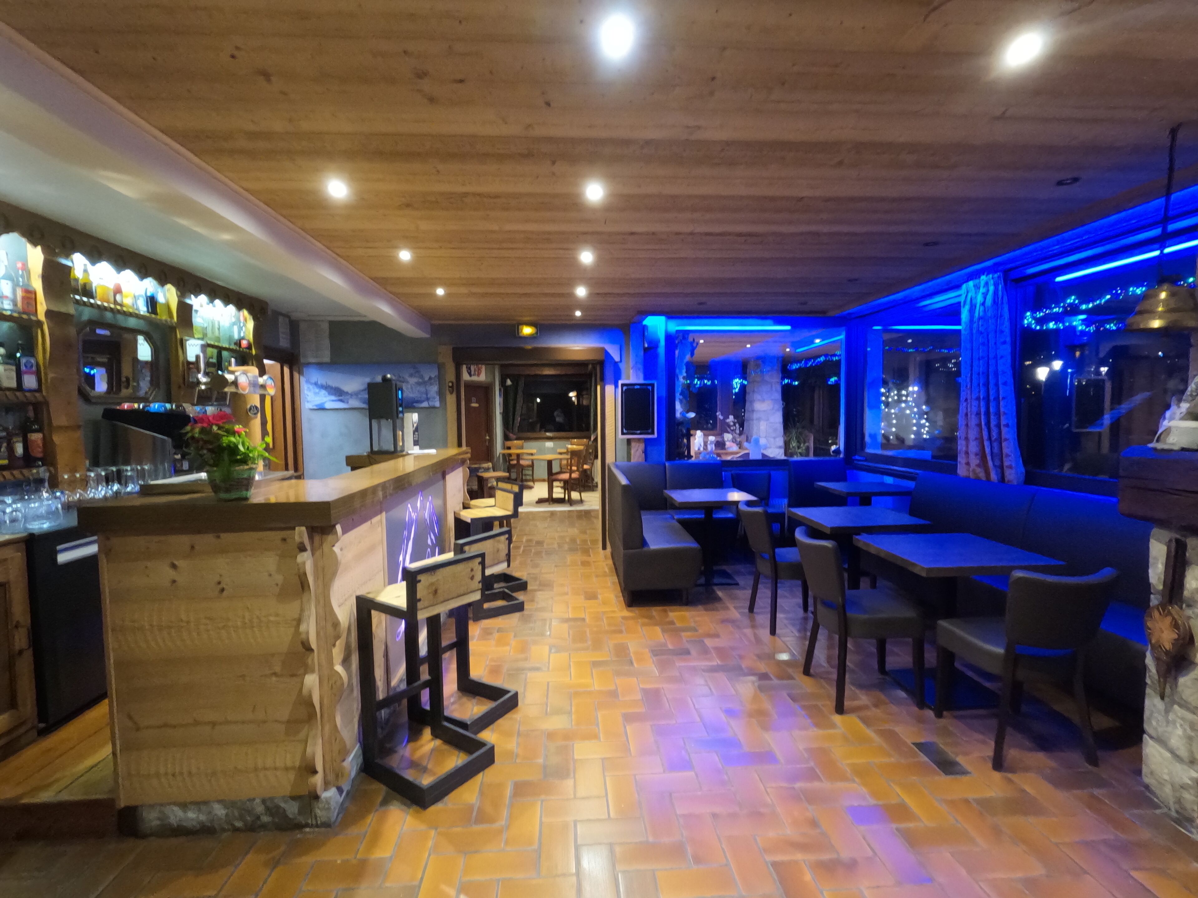 A restaurant with wooden flooring, a bar area, and seating arrangements.