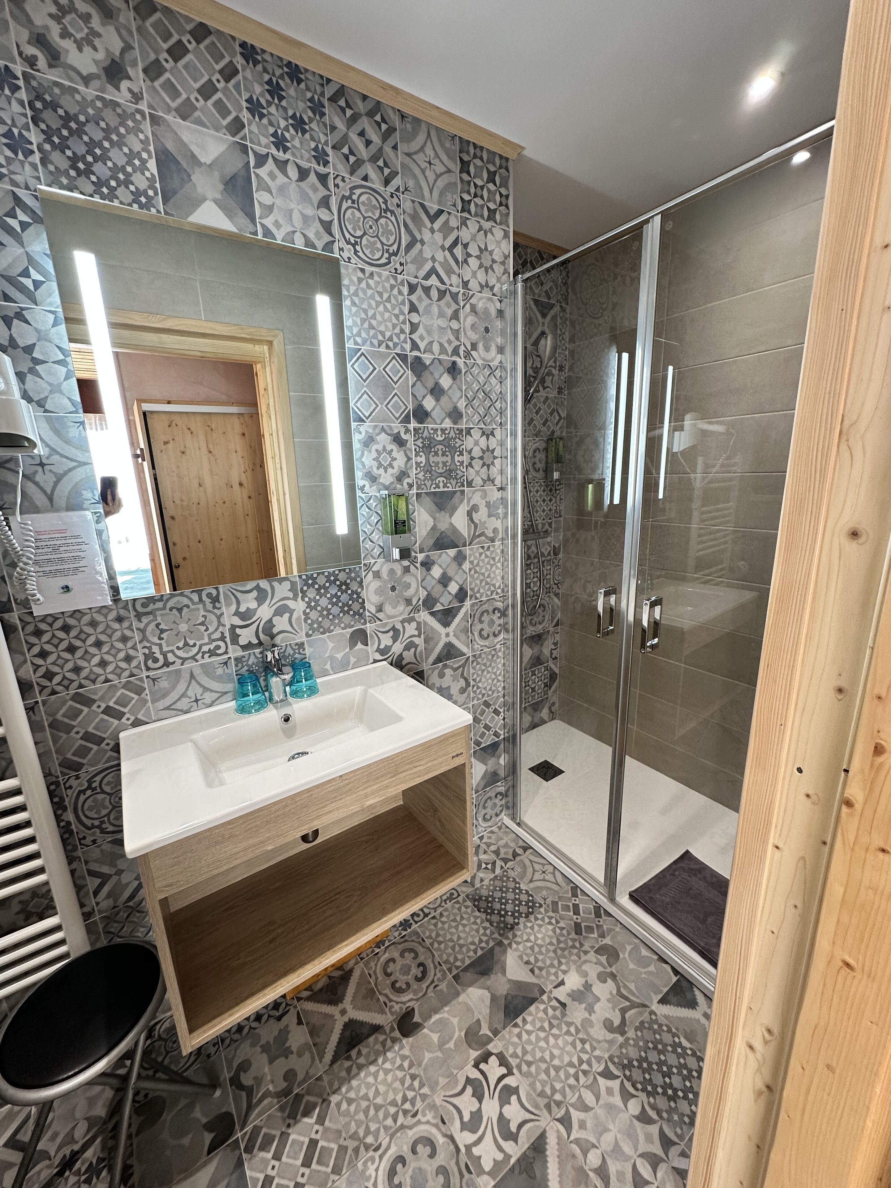 Une salle de bain avec un lavabo blanc, un miroir et des carreaux à motifs.