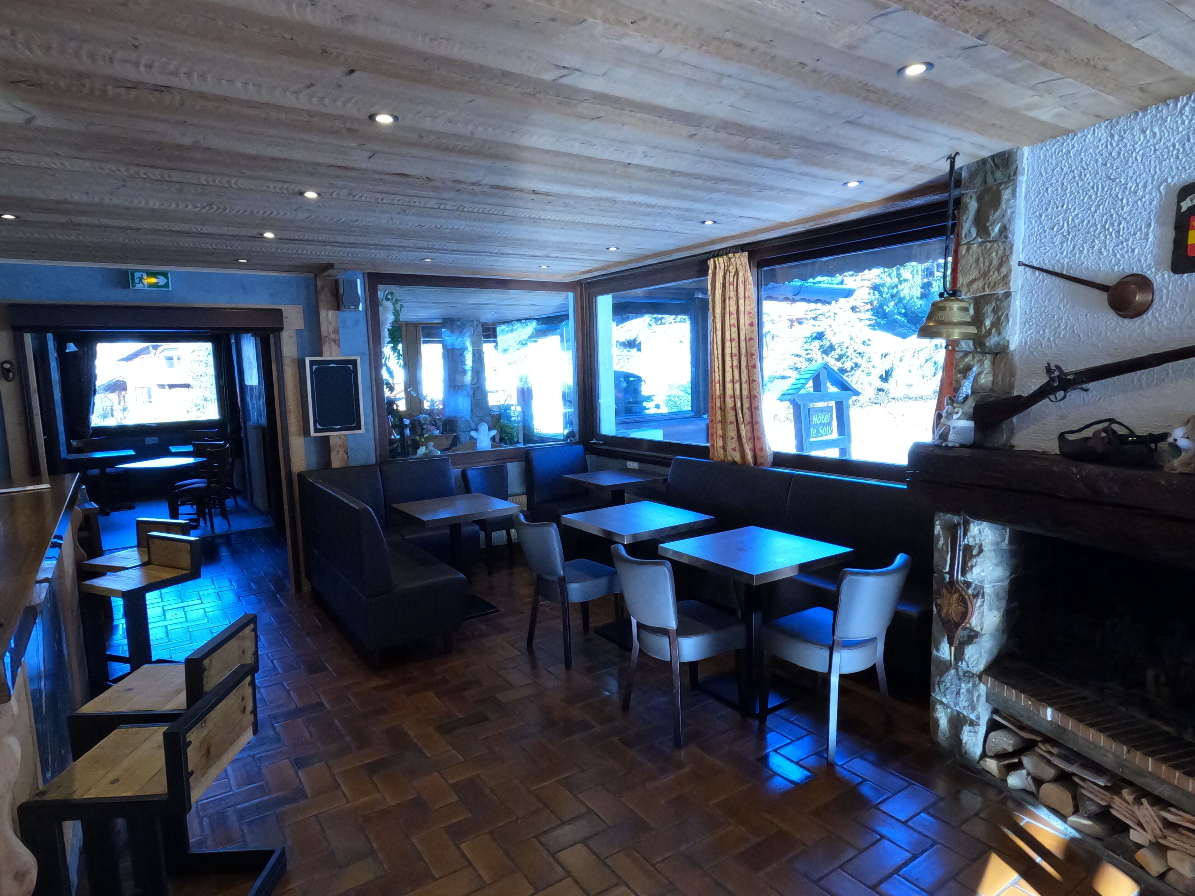 Un ristorante con pavimento in legno, tavoli, sedie e un camino.