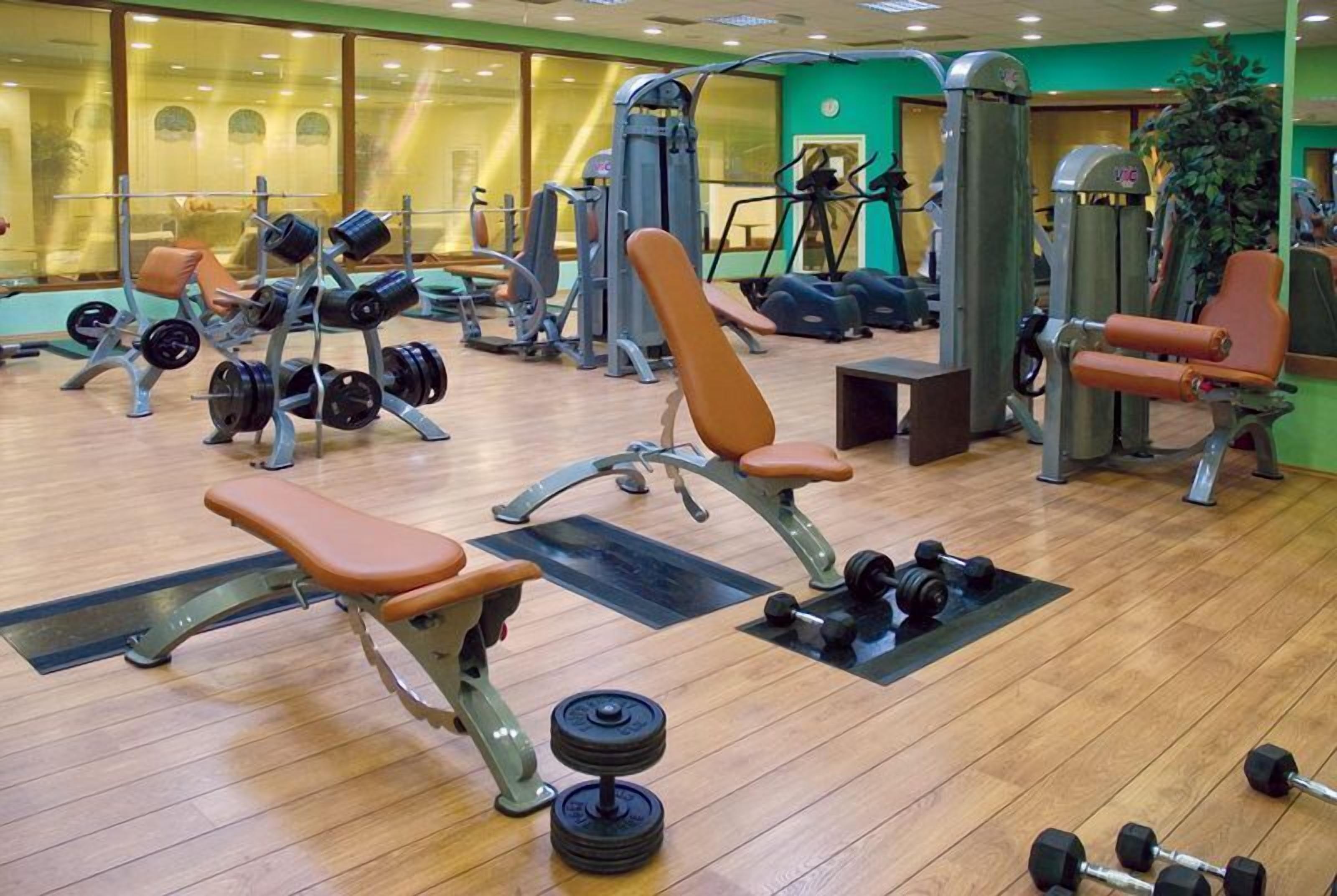 Un gimnasio con diverso equipo de ejercicio, incluyendo bancos, mancuernas y máquinas de pesas.