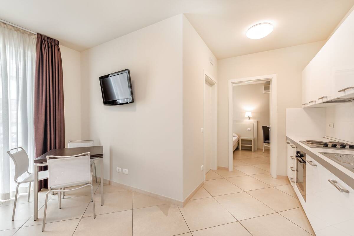 A modern kitchen with a built-in oven and a dining area with a table and chairs.
