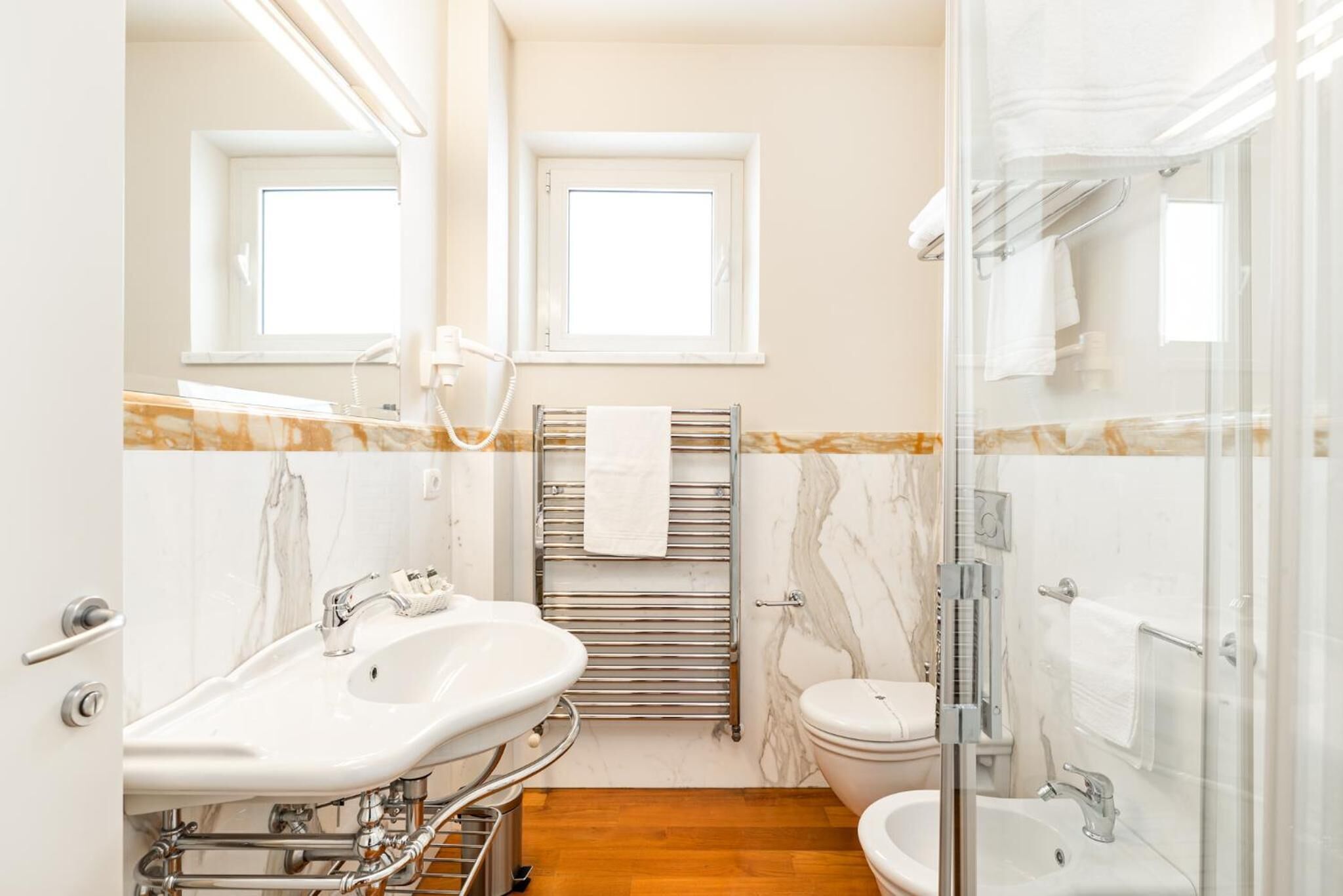 A modern bathroom with a double sink, toilet, and shower area.