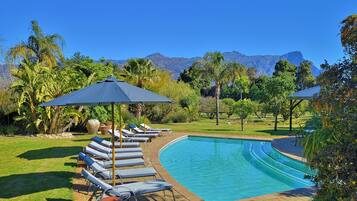 Alberca al aire libre, sombrillas en la alberca y camastros