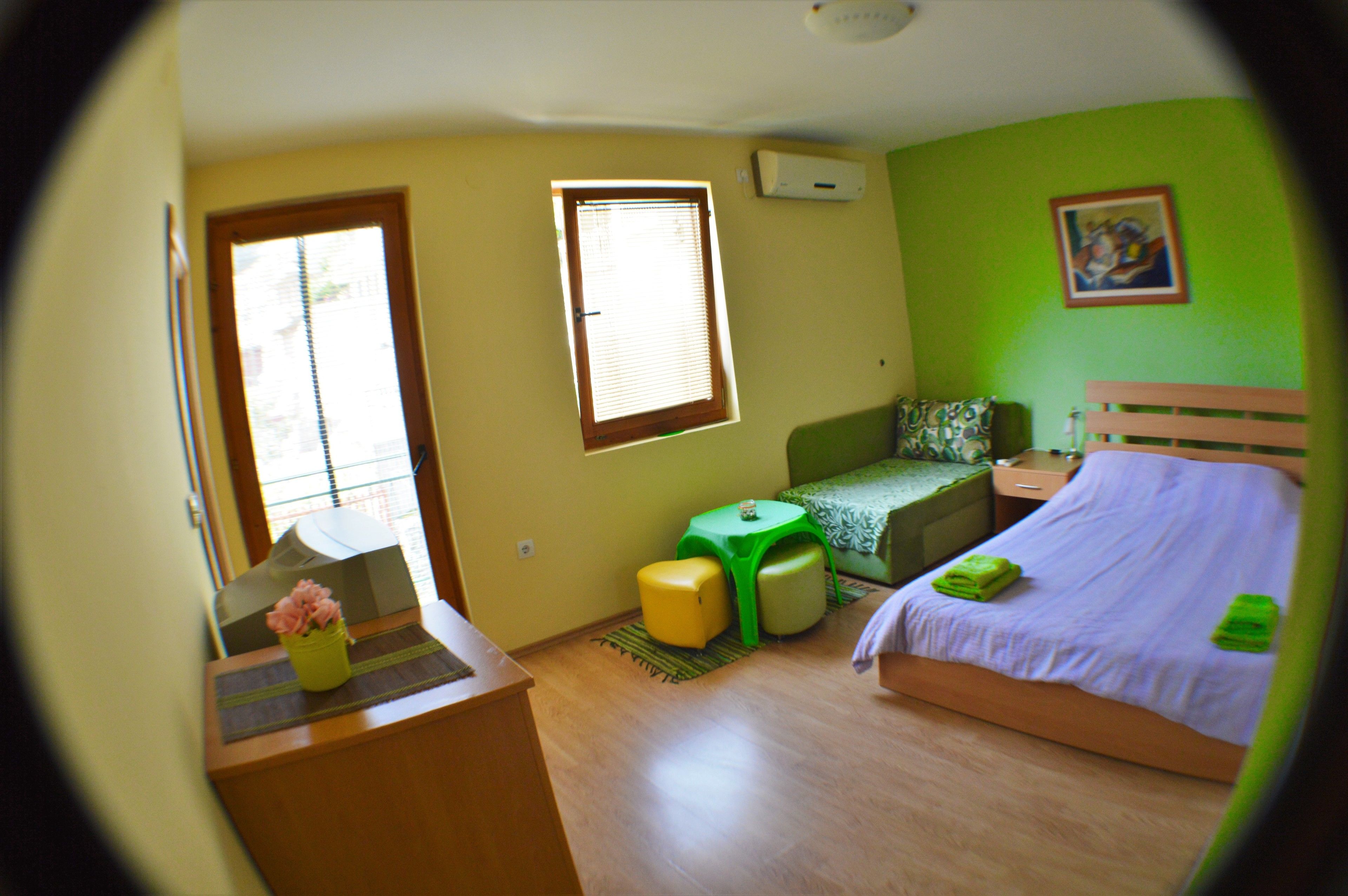 A room with a bed, a desk, a chair, a small table, and a window.