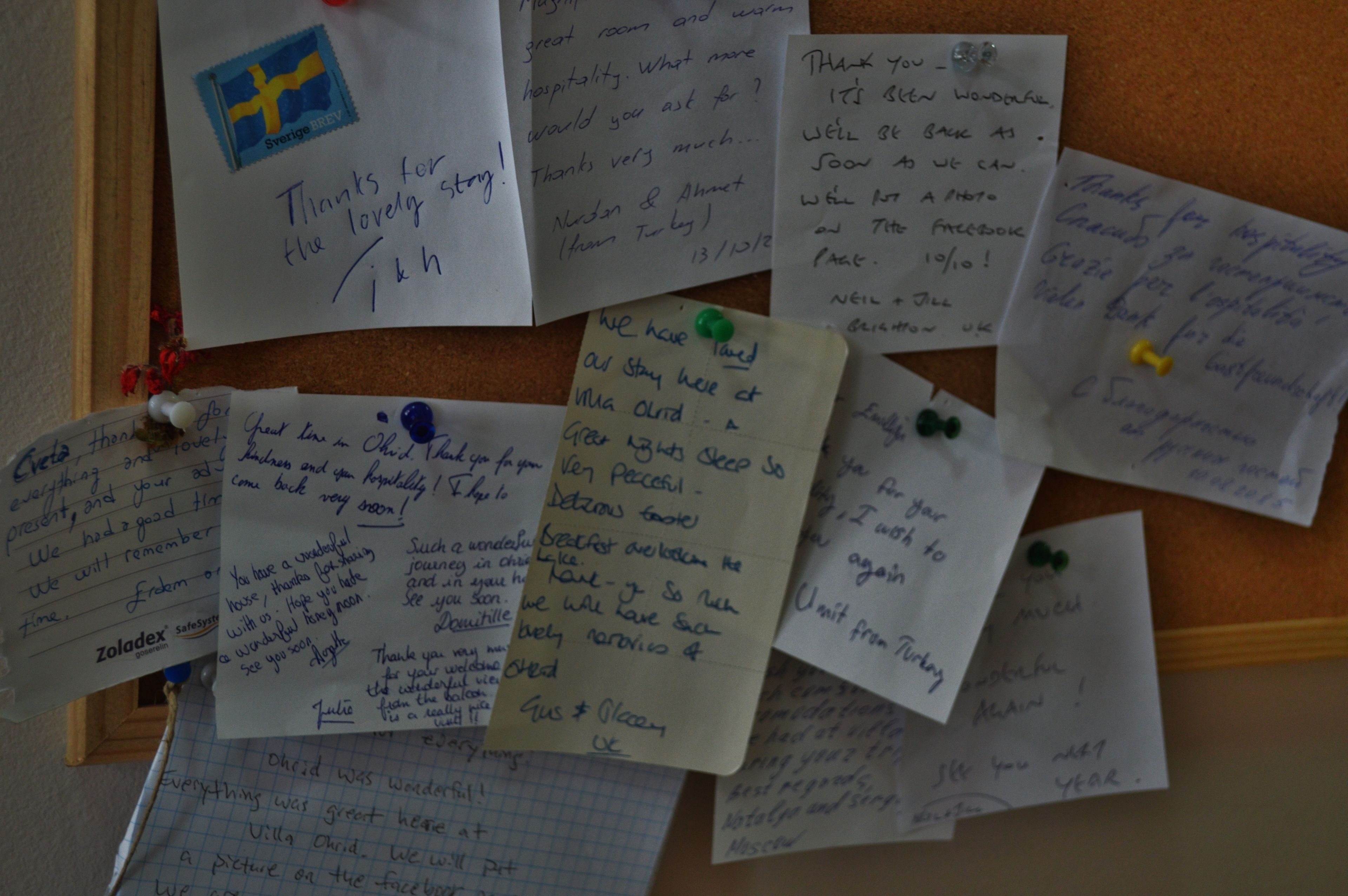 A corkboard with handwritten notes pinned to it, including messages of thanks and mentions of a hotel stay.