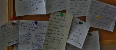 A corkboard with handwritten notes pinned to it, including messages of thanks and mentions of a hotel stay.