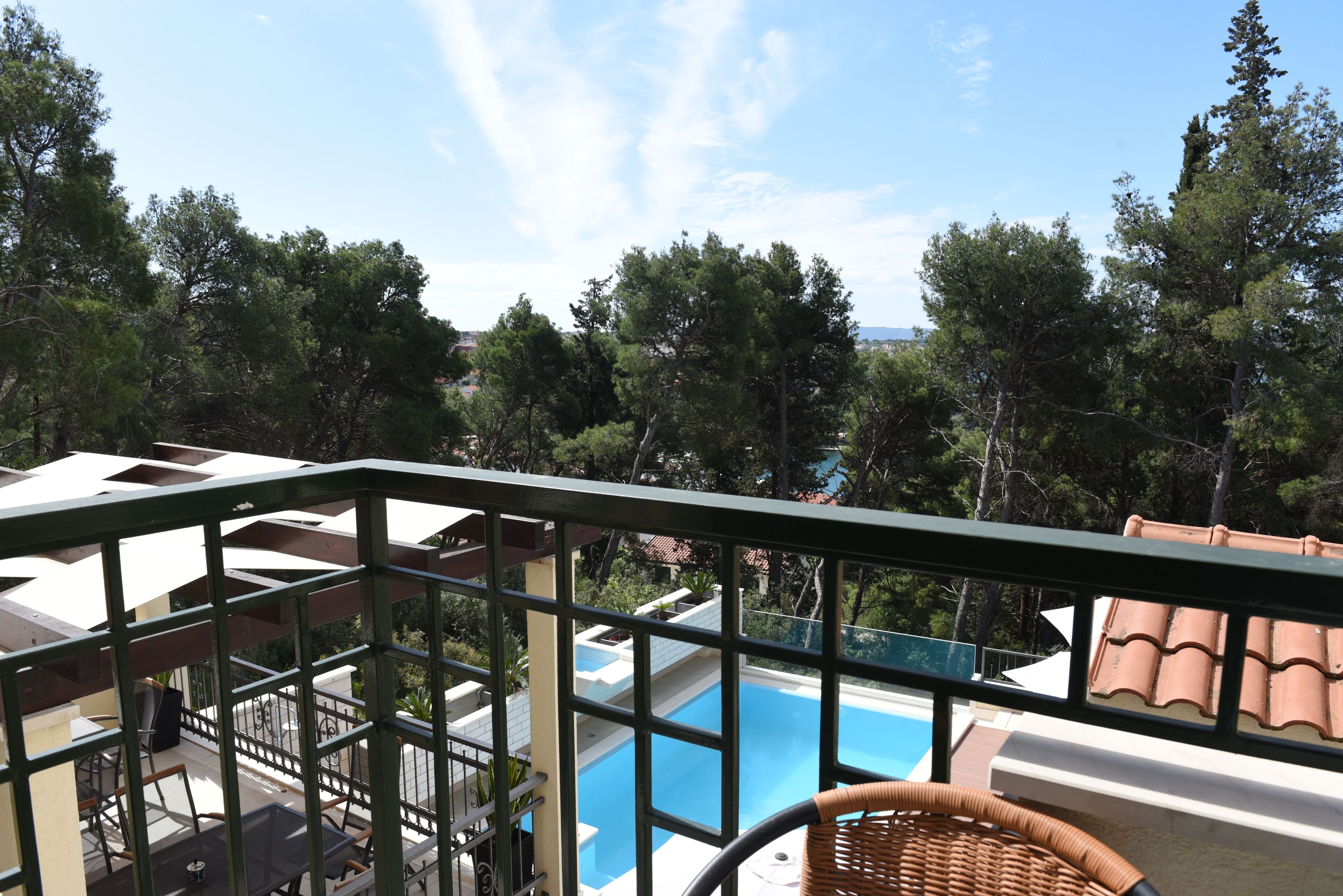 Un balcón con vistas a una piscina, rodeado de árboles y edificios.