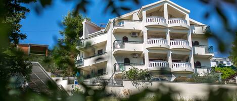 A multi-story building with balconies, a staircase, and a clear blue sky.