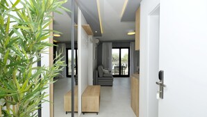 A modern living room with a sofa, a wooden bench, and a glass partition. - Villa Fani - Apartments and Rooms (Trogir)