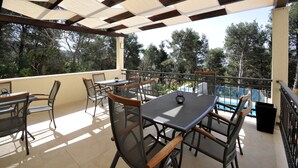 An outdoor patio with tables and chairs, a pool in the background, and trees around. - Villa Fani - Apartments and Rooms (Trogir)