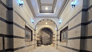 Una imponente entrada con una amplia escalera, luces empotradas en la pared y un techo decorativo.