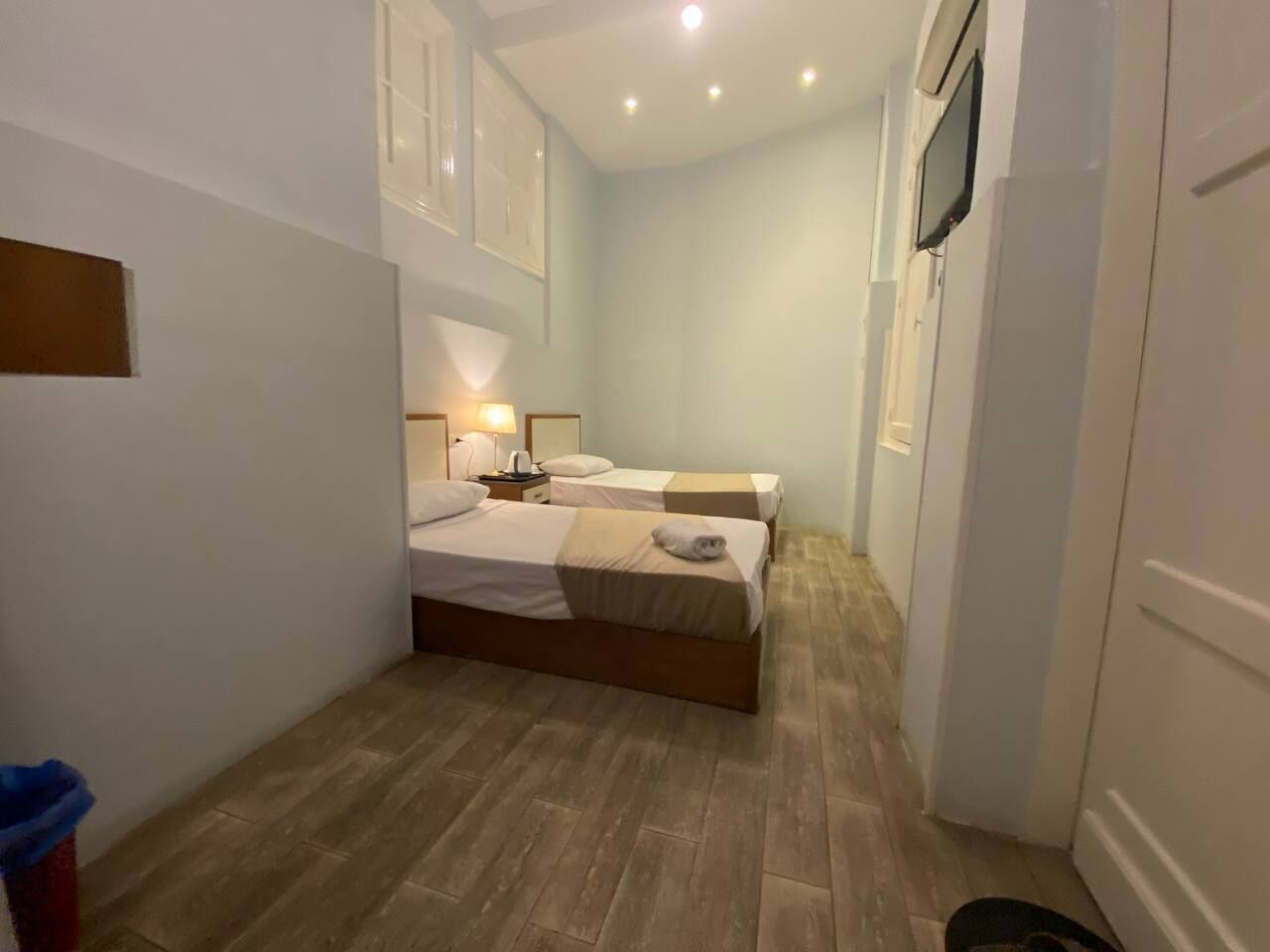 A small room with two beds, a wooden floor, and a white wardrobe.