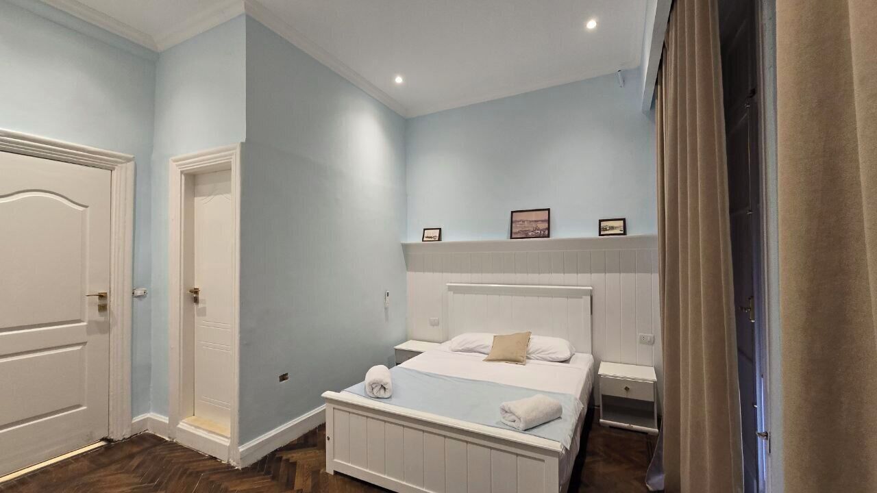 Een slaapkamer met een bed, nachtkastjes en een deur.