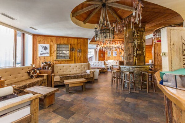 A cozy, rustic interior with wooden walls, a large chandelier, and a bar area. - Hotel Principi di Piemonte Sestriere (Sestriere)