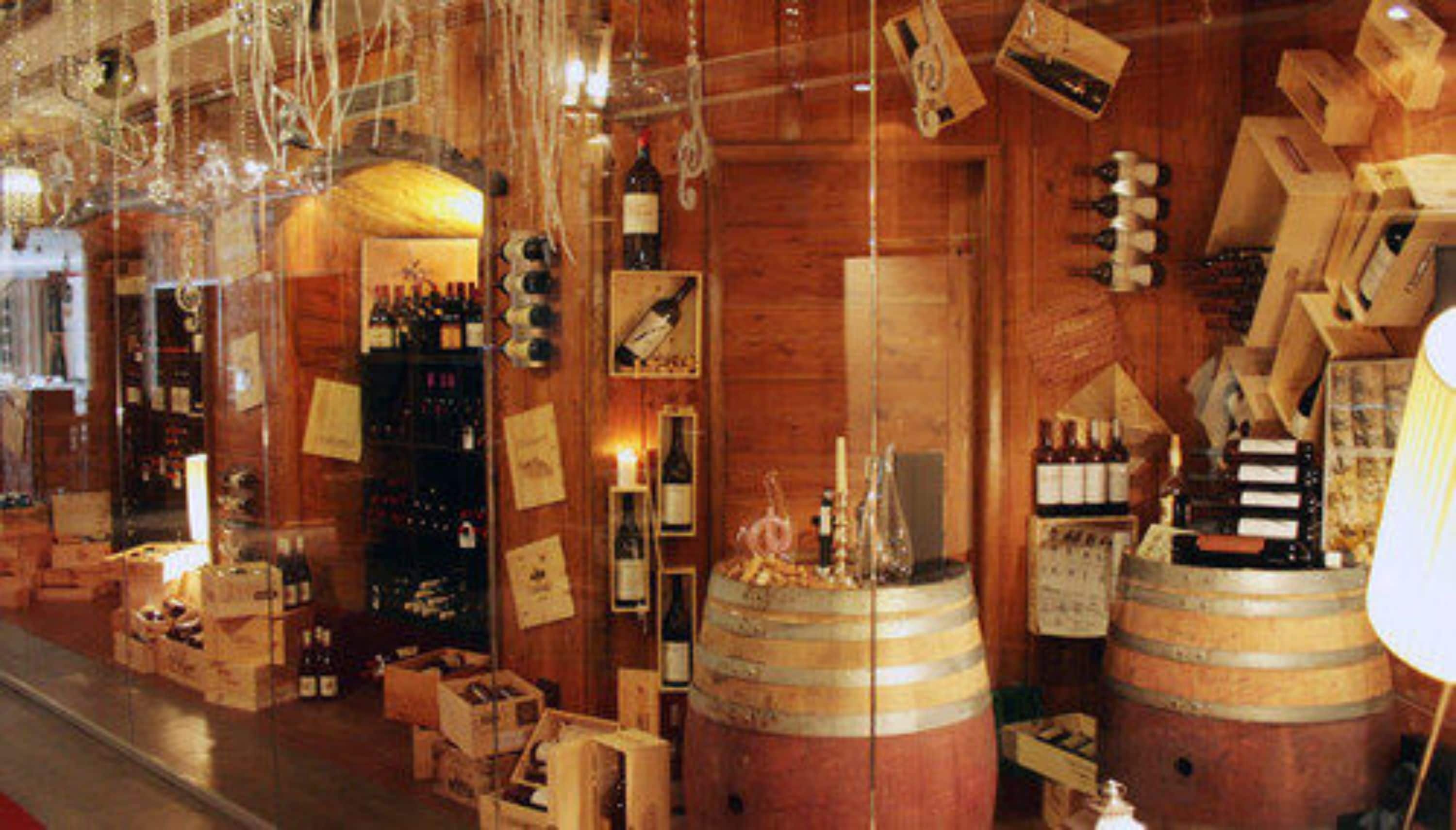 A wooden interior with barrels, wine bottles, and wooden boxes.