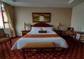 Habitación de hotel con una cama grande, un banco, un escritorio y una silla.