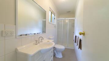 A modern bathroom with a white sink, toilet, and shower.