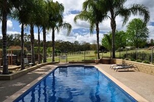 Una piscina al aire libre, sillones reclinables de piscina
