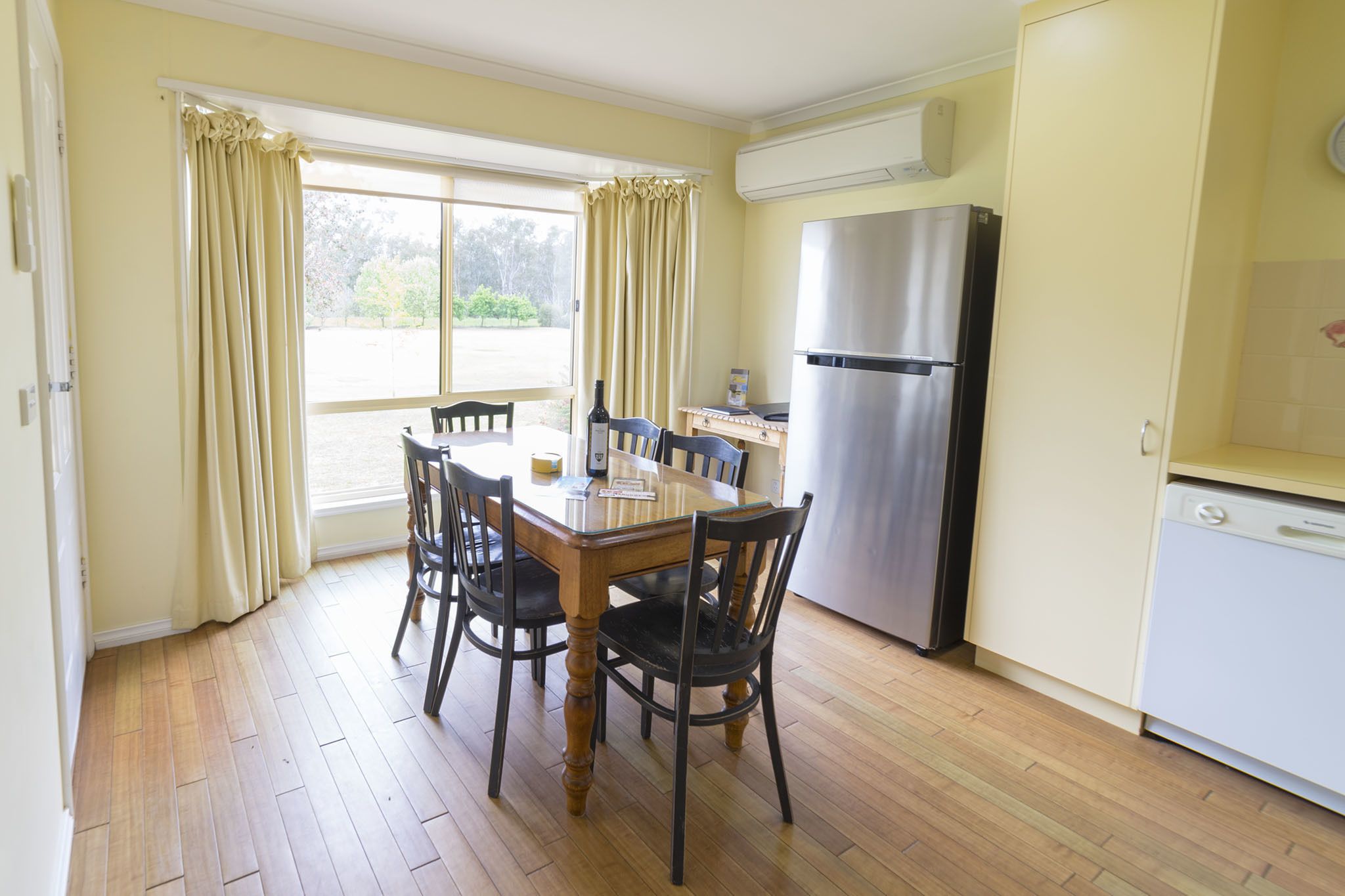 A dining area with a wooden table and chairs, a refrigerator, and a dishwasher.