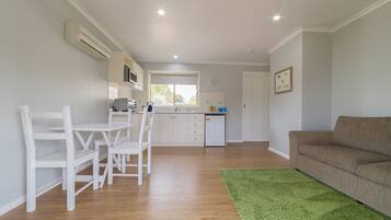 Une cuisine moderne avec des meubles blancs, un coin repas avec des chaises blanches et un tapis vert.