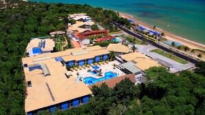 An aerial view of a resort with multiple buildings, a swimming pool, and a beach.