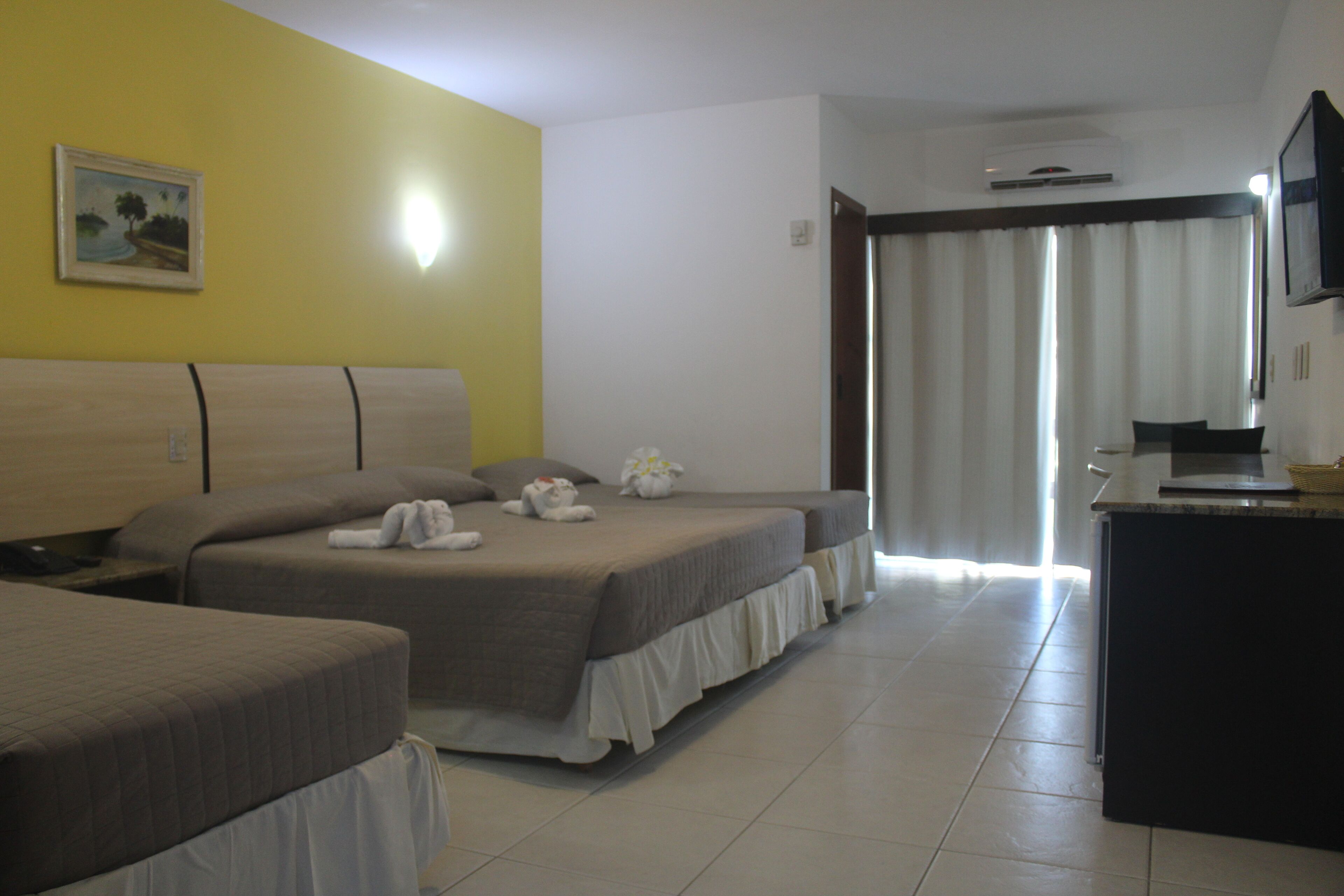 A hotel room with two beds, a desk, and a television.