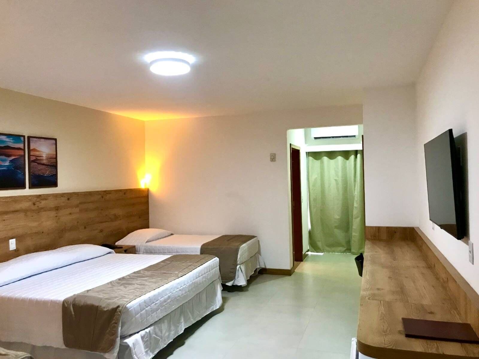 A hotel room with two beds, a TV, and a wooden headboard.