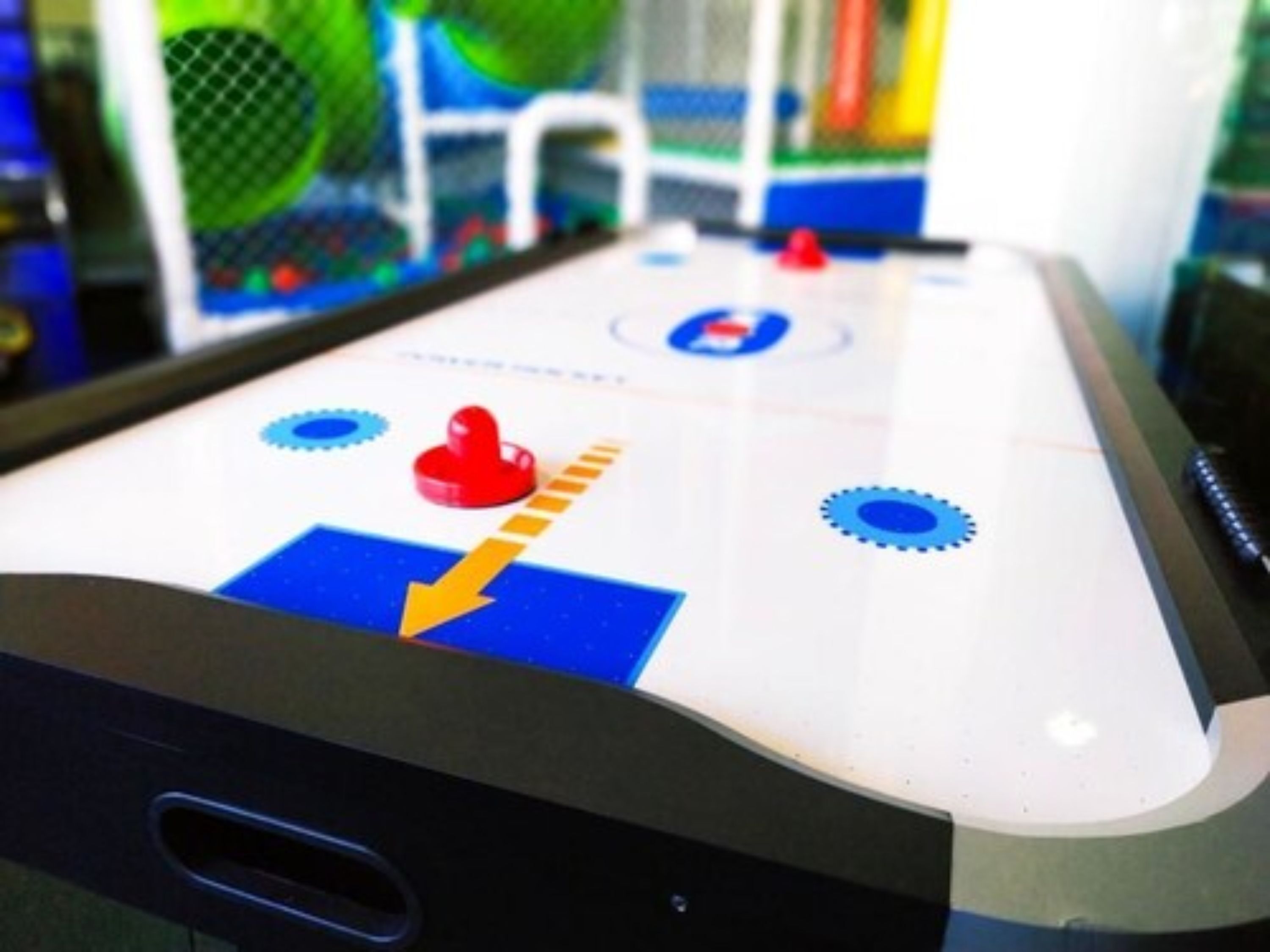 Une table de jeu de palet avec un palet rouge, des repères bleus et jaunes, et un fond blanc.