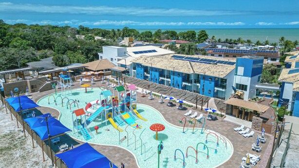 A resort with a large swimming pool, water slides, and sun loungers.