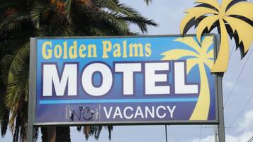 Segnaletica di motel con la scritta "Golden Palms Motel" e un'immagine di una palma.