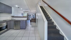 A modern kitchen with grey cabinets, a dishwasher, and a built-in oven. - Getaway On Grafton (Cairns)