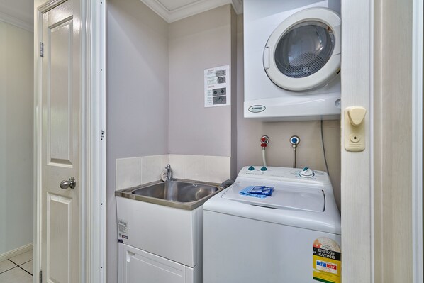 A laundry room with a washing machine, a dryer, and a sink. - Getaway On Grafton (Cairns)