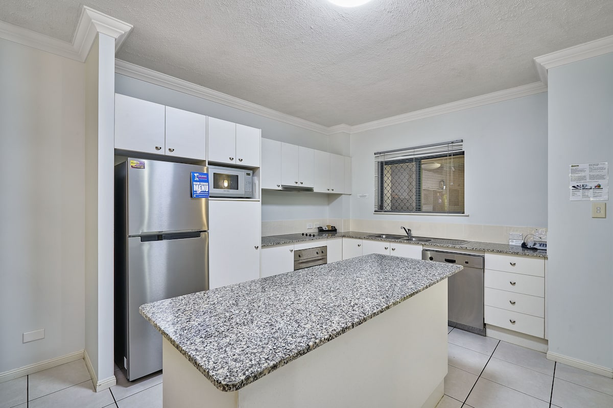 A modern kitchen with white cabinets, stainless steel appliances, and a granite countertop.