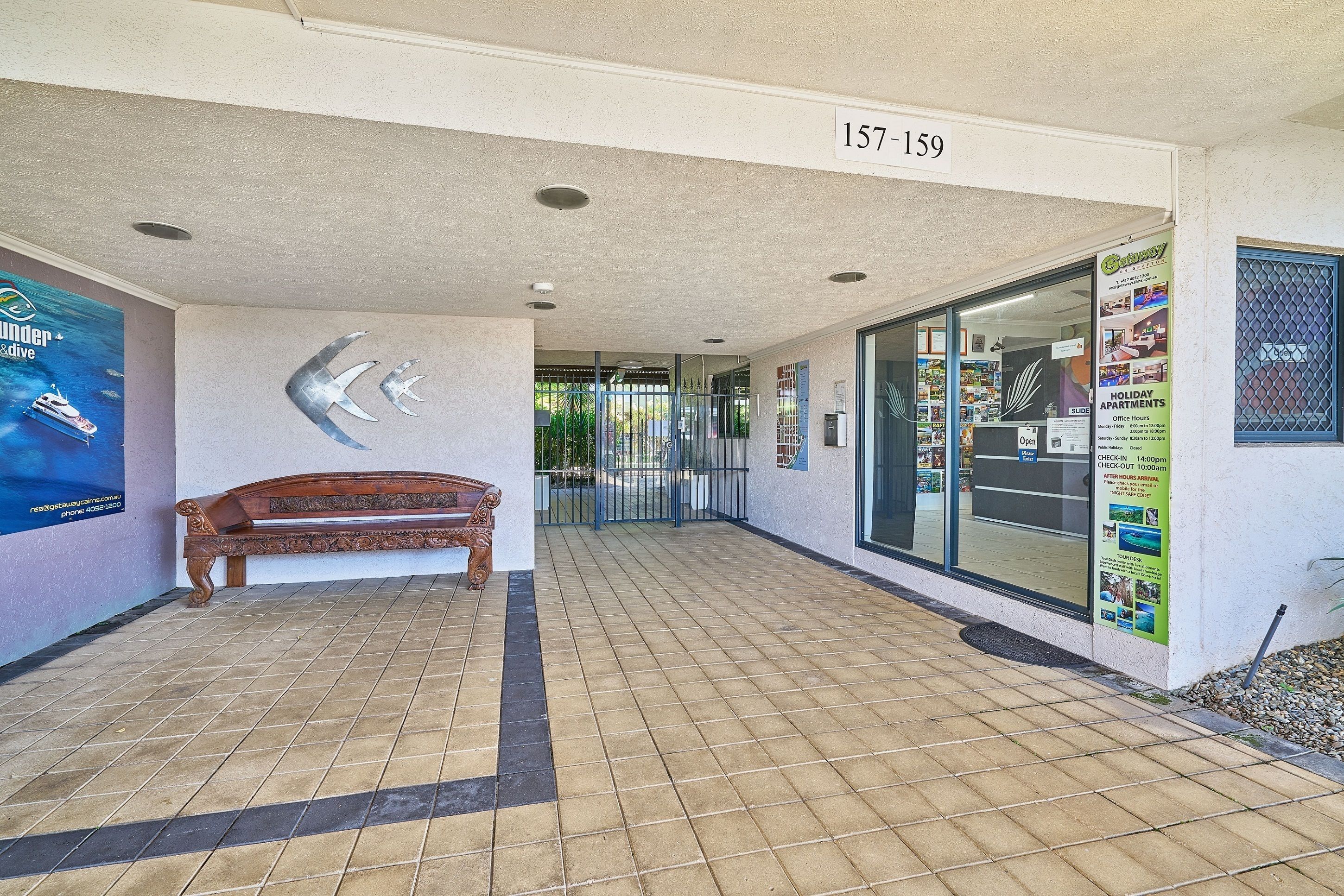 A building entrance with a bench, a sign with the number 157-159, and a glass door leading inside.