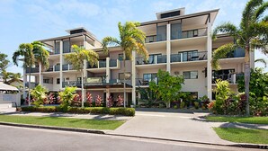 A multi-story hotel with balconies, surrounded by tropical plants and a clear sky. - Getaway On Grafton (Cairns)