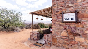 Un edificio de piedra con un letrero que dice "KAGGA KAMMA SALON" y una pérgola de madera con cestas colgantes.