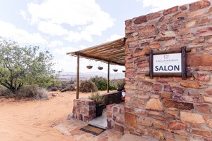 Un edificio de piedra con un letrero que dice "KAGGA KAMMA SALON" y una pérgola de madera con cestas colgantes.