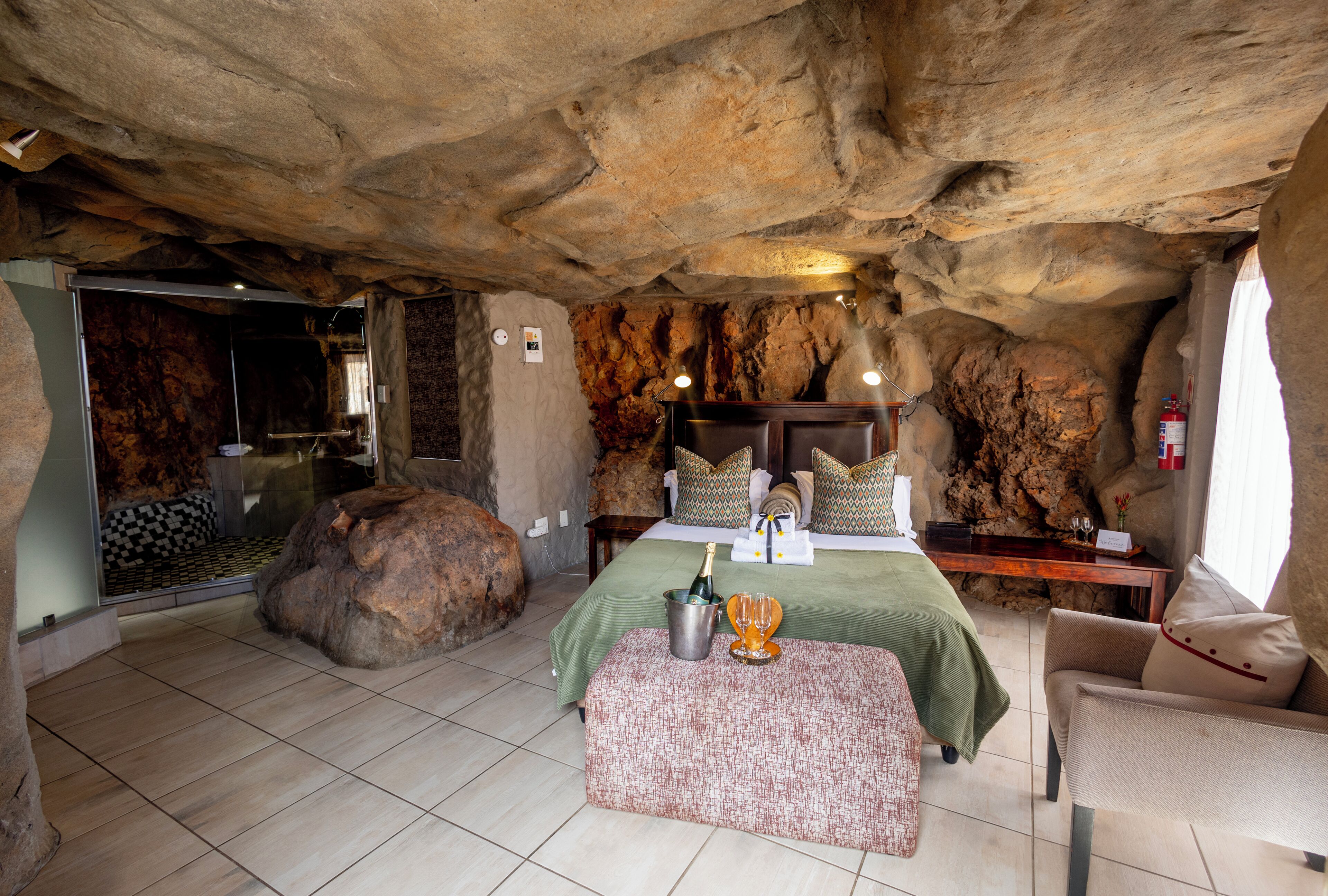 Un dormitorio con temática de cueva, que incluye una cama, una zona de estar y una gran roca decorativa.
