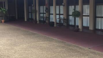 Een gebouw met een overdekt terras, zuilen en potplanten.