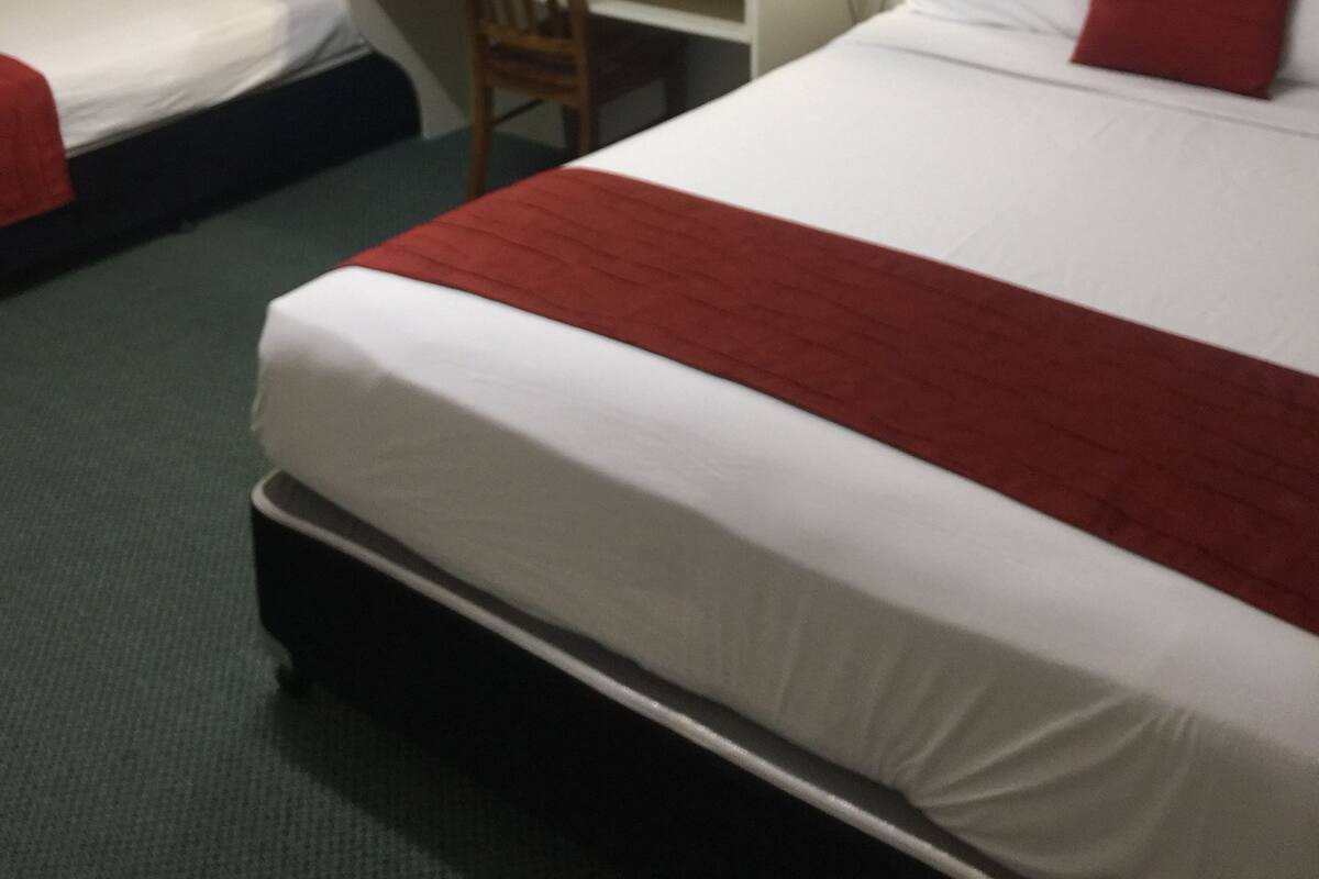 Habitació d'hotel amb dos llits, una taula de treball, una cadira, un mirall i una finestra amb cortines.